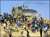 Palestinian youths throw stones at Israeli bulldozers in Beit Lahiya, Gaza