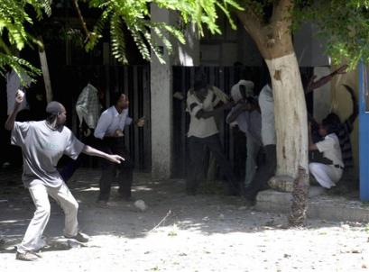 Sudanese refugees stoning Egyptian riot police Wednesday, Aug. 25, 2004 as about 500 refugees from Sudan's volatile Darfur region clashed with tear gas-firing Egyptian police outside the  U.N. refugee headquarters in Cairo. The protestors demanded better treatment from the U.N. agency and called on international peacekeepers be sent to Darfur to disarm Arab militias blamed for killing 30.000 people and driving more than 1 million from their homes. (AP Photo/Hasan Jamali)