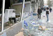 Passers by look into the smashed windows of a shop in the center of Kyrgyz capital Bishkek March 25. Kyrgyzstan's newly formed interim government is taking measures to restore order in the Central Asian country after two days of unrest that left the government collapsed and three people dead.