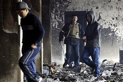 A Kyrgyz volunteer drives away people from a damaged and looted shopping mall in Bishkek / Photo: AP
