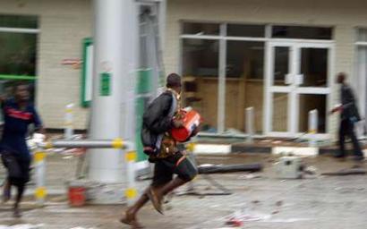 Looters flee with their ware as riots sweep Malawi's commercial capital Blantyre, May 23, 2004. Malawi police fired warning shots to break up protests on Sunday over ruling party candidate Bingu wa Mutharika becoming the new president in a general election the opposition says was rigged.  REUTERS/Salim Henry
